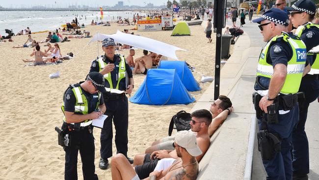 Police issue a fine or warning to some young men for drinking at St Kilda beach. Picture: Jason Edwards