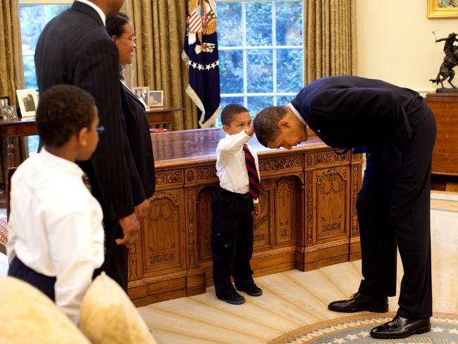 President Barack Obama bends over so the son of a White House staff member can pat his head during a visit to the Oval Office on May 8, 2009 in Washington, DC. Picture: Pete Souza/The White House