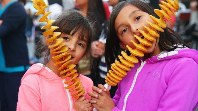 Friends Sophie and Maya from Blacktown tuck into a potato kebab at the Aussie Night Markets debut at the Village Green.