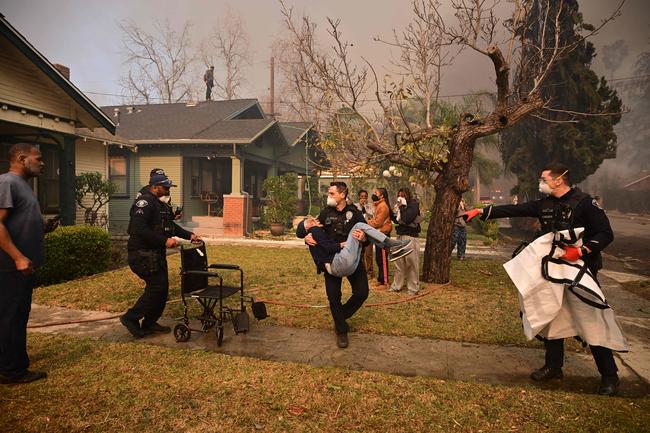 Police remove an eldery resident from her home in Altadena. Picture: AFP