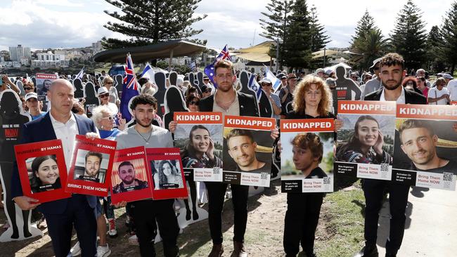 From left Elad Levy, Lior Vizental, Amit Parpara, Tali Kizhner and Ofir Tamir holding photos of Jewish family and friends who are hostages held by Hamas, during an event at Bondi Beach. Picture: Jonathan Ng