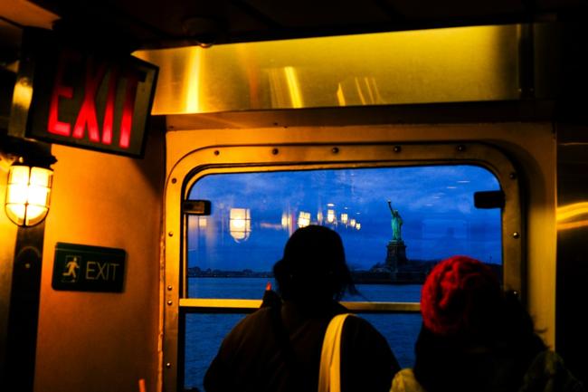 Passengers take photos of the Statue of Liberty, another popular tourist attraction, as they ride the Staten Island ferry