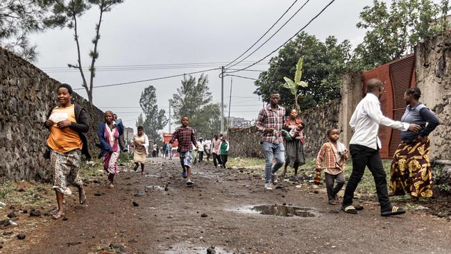 Residents run off after watching members of the M23 armed group walking through a Goma street on Monday. Picture: AFP