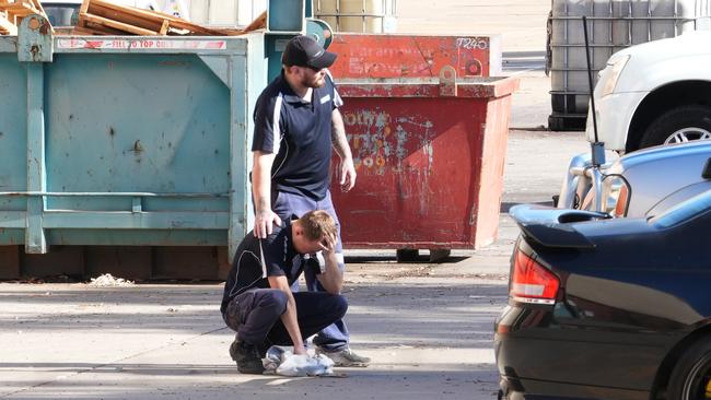 An emotional worker is consoled by a colleague in the carpark of the business after the incident. Picture: Dean Martin