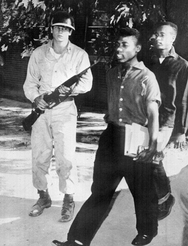 US paratroopers in full battle dress escort nine black children — three boys and six girls — into Little Rock Central High School in 1957.