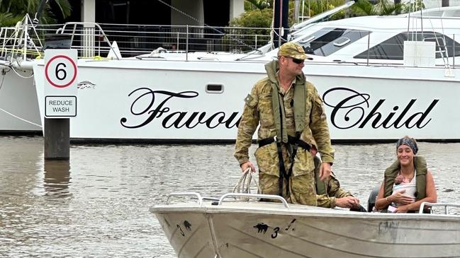 Private Scott Garden, from 51st Far North Queensland Regiment, assisting in the evacuation of a mother and child in the Northern Beaches of Cairns.