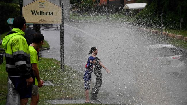 Children cop a spray as motorists drive through floodwaters near Warragamba Dam in Sydney on Sunday. Picture: AFP