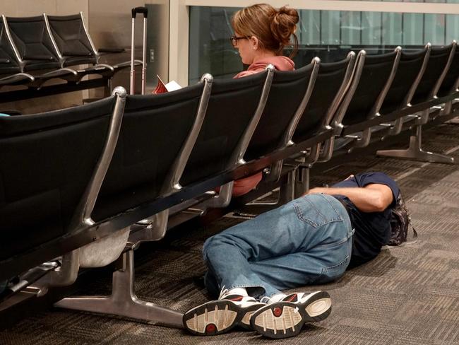 DETROIT, MICHIGAN - JULY 20: Travelers rest where they can in the McNamara terminal at the Detroit Metropolitan Wayne County Airport on July 20, 2024, in Detroit, Michigan. Many travelers were rerouted or had their flights canceled as the world continues to be affected by a global technology outage attributed to a software update administered by CrowdStrike, a cybersecurity firm whose software is used by various industries worldwide.   Joe Raedle/Getty Images/AFP (Photo by JOE RAEDLE / GETTY IMAGES NORTH AMERICA / Getty Images via AFP)