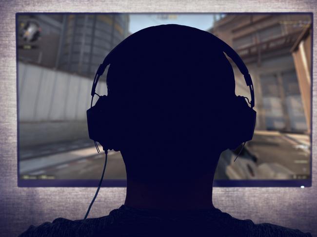 Gamer in headphones sits in front of a blank monitor in dark room