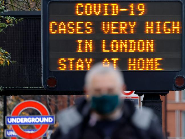 Pedestrians pass a sign alerting people to the pandemic in London last week. Picture: AFP