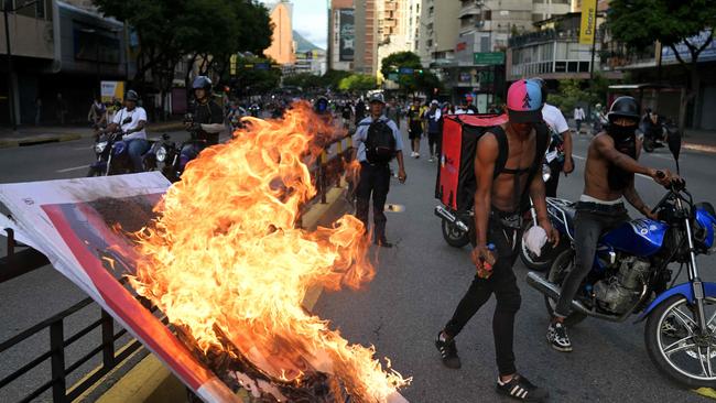 Demonstrators burn an advertisement banner. Picture: YURI CORTEZ / AFP