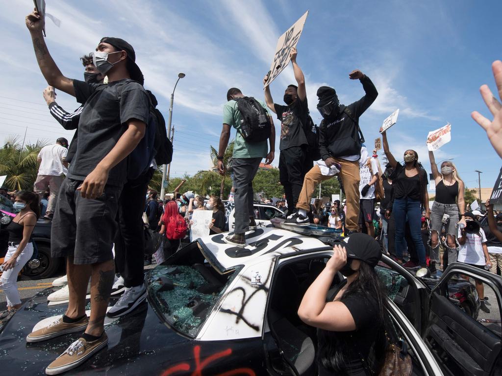 Demonstrators stand on a smashed police vehicle in the Fairfax District as they protest the death of George Floyd in Los Angeles. Picture: Mark Ralston/AFP