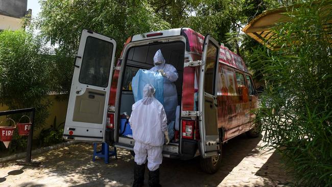 Health workers get ready near a mobile coronavirus testing van near Ahmedabad in India on Friday. Picture: AFP