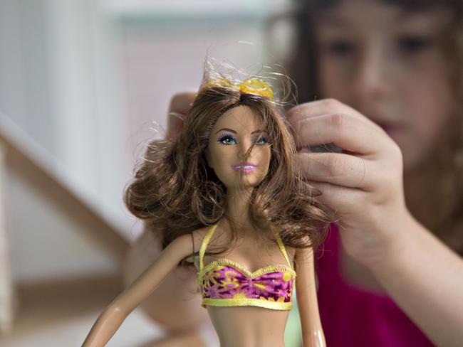 A young girl plays with a Mattel Inc. Barbie doll in Tiskilwa, Illinois, U.S., on Wednesday, July 1, 2015. Photographer: Daniel Acker/Bloomberg