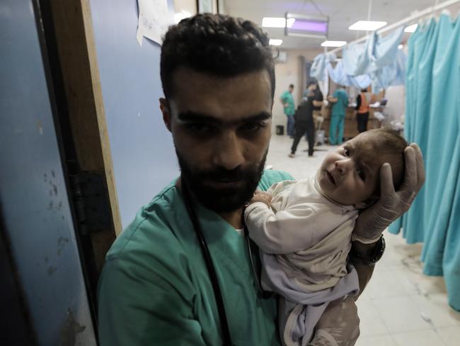 A medic carries a baby as Palestinians injured in air strikes arrived at Nasser Medical Hospital in November. Picture: Getty Images