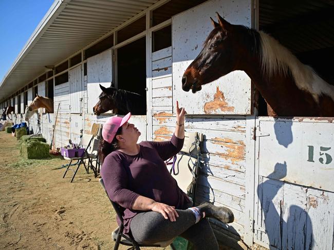 A woman sits by her horse, soothing it, after being evacuated from the Eaton Fire to the Los Angeles Equestrian Centre in Burbank, California. Picture: Agustin Paullier/AFP