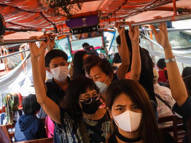 TOPSHOT - Passengers wearing protective facemasks stand in a commuter ferry boat on the San Saeb Canal in Bangkok on February 5, 2020. - Thailand so far has detected 25 confirmed cases of the novel coronavirus believed to have originated in the central Chinese city of Wuhan, which is under lockdown. (Photo by VIVEK PRAKASH / AFP)