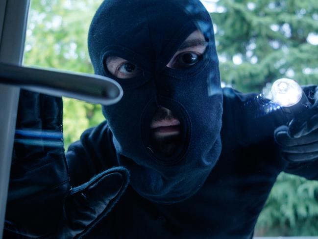 Burglar wearing a balaclava looking through the house window