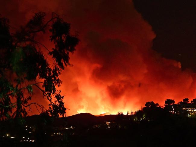 Smoke and flames from the Palisades Fire burn toward the Encino neighborhood of Los Angeles, California, January 10, 2025, triggering new evacuation orders. Massive wildfires that engulfed whole neighborhoods and displaced thousands in Los Angeles have killed at least 10 people, authorities said, as California's National Guard soldiers readied to hit the streets to help quell disorder. News of the growing toll, announced late Thursday January 9 by the Los Angeles County Medical Examiner, came as swaths of the United States' second-largest city lay in ruins. (Photo by AGUSTIN PAULLIER / AFP)