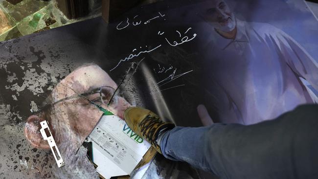 A man steps on a damaged portrait of slain Hezbollah leader Hassan Nasrallah and Iran's late general Qassem Soleimani as Syrians loot the Iranian embassy in Damascus. Picture; AFP.