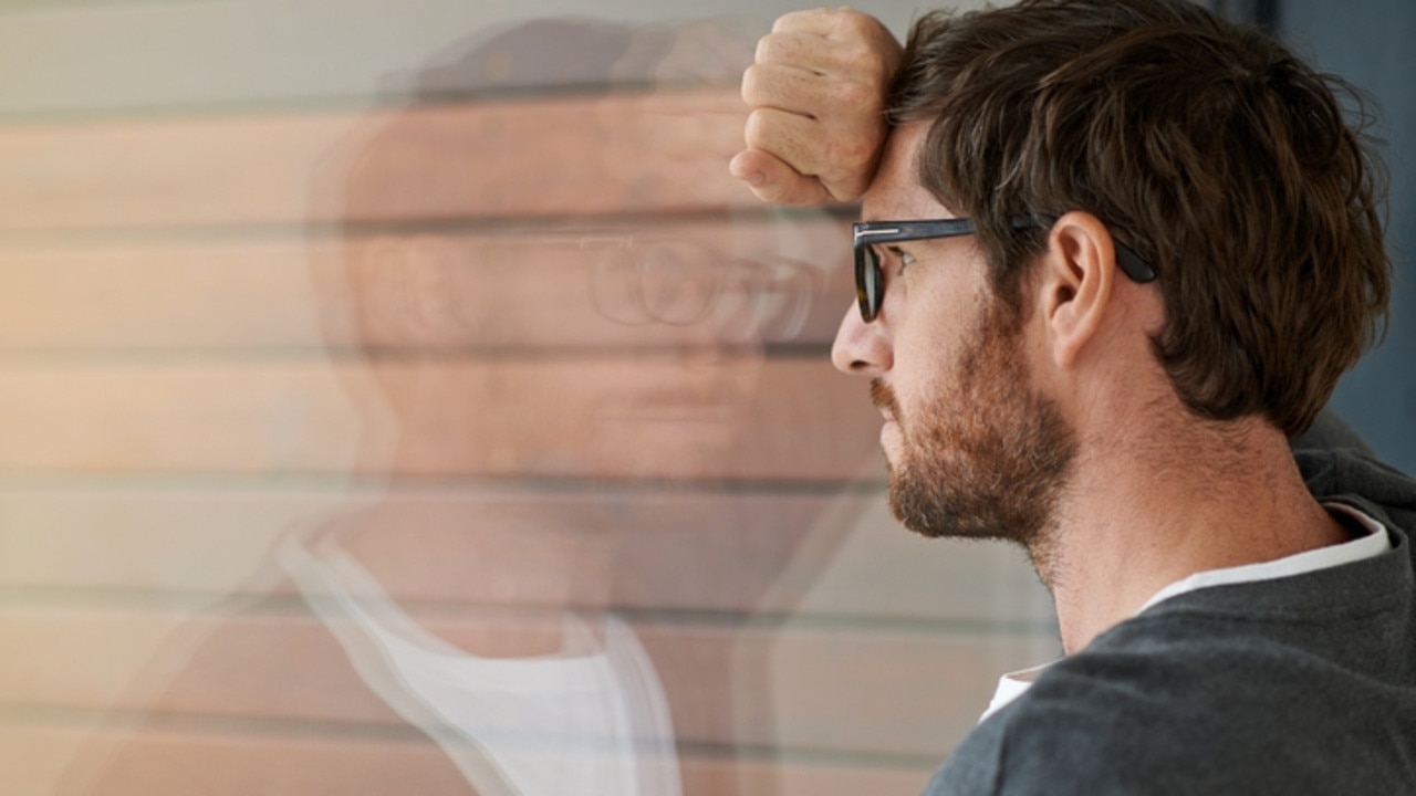 Lonely man leaning against a glass window in his office. (Pic: iStock)