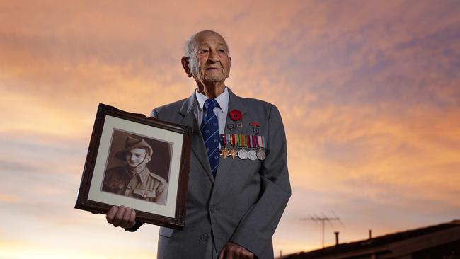 WWII veteran Jack Hair, 97, stands outside his home with a portrait of himself at dawn