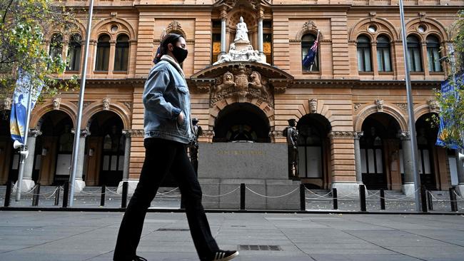 A woman wearing a face mask walks through a quiet Martin Place in Sydney. Picture: AFP