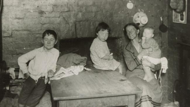 A family sits in the kitchen of a ramshackle house in Carlton. Picture: F. Oswald Barnett collection, State Library of Victoria