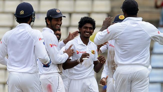 Sri Lanka's Lakshan Sandakan (C) smiles after bowling Austraila’s Joe Burns.