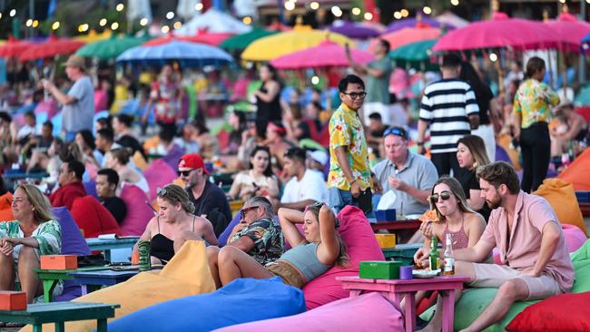 Foreign tourists relax on the Kuta Beach near Denpasar on Indonesia's resort island of Bali on November 18, 2023. (Photo by SONNY TUMBELAKA / AFP)