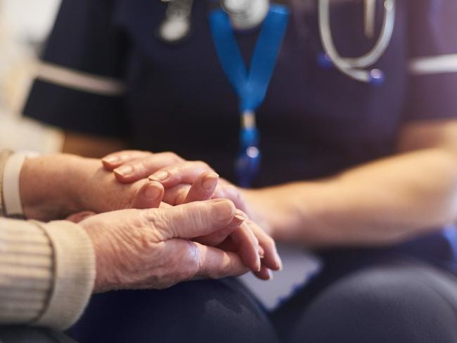 A female nurse consoles a senior patient at home, aged care generic