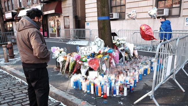 Flowers, candles and balloons form part of a growing memorial outside of the 32nd Police Precinct in Harlem days after a shooing left one officer dead and a second in critical condition on January 24 in New York City.