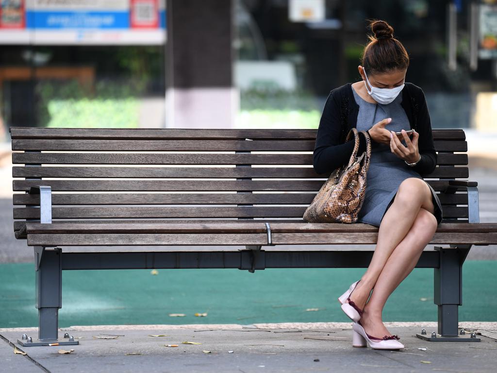 A woman with a face mask sits on a bench in central Brisbane. Picture: Dan Peled