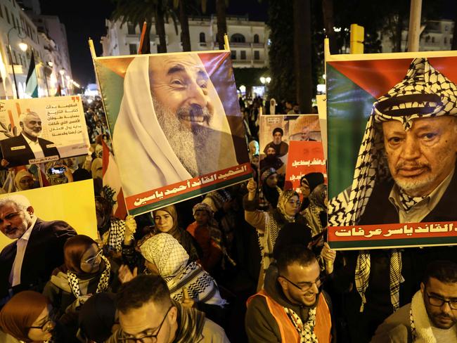 People raise placards bearing pictures of slain Hamas spiritual leader Sheikh Ahmad Yassin (C) late PLO leader Yasser Arafat (R) and slain Palestinian Hamas political leader Ismail Haniyeh, as they take part in a rally marking the annual Quds Day (Jerusalem day) commemorations in Rabat, late on March 28, 2025. Quds Day is commemorated in support of the Palestinians annually on the last Friday of the Muslim holy month of Ramadan by an initiative started by late Iranian revolutionary leader Ayatollah Ruhollah Khomeini. (Photo by Abdel Majid BZIOUAT / AFP)