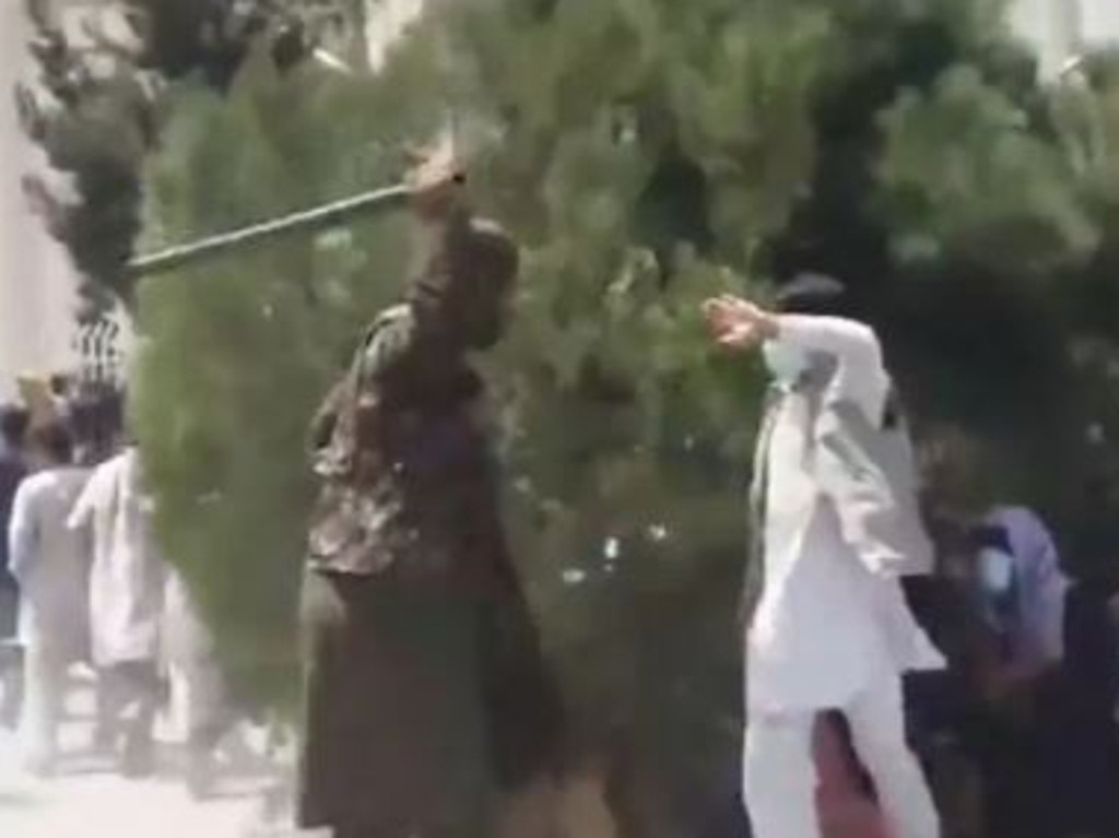 A Taliban fighter beats a man on the street as people run. Picture: Supplied