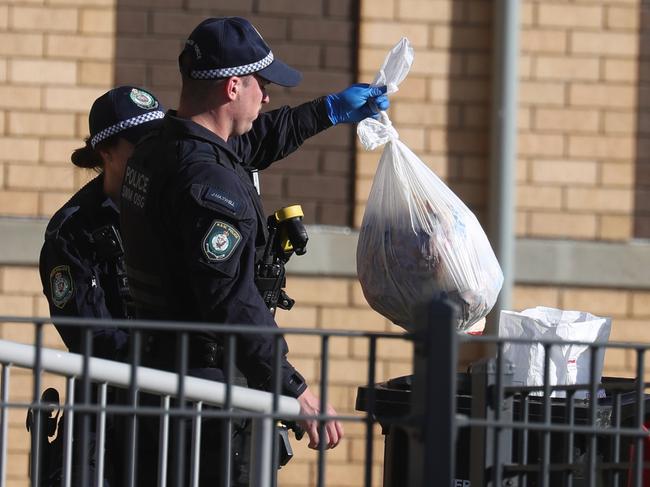 Police sift through garbage around the apartment block looking for evidence. Picture: John Grainger