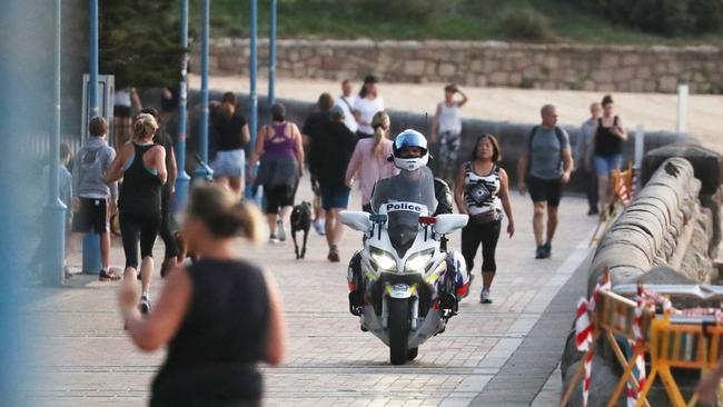 A motorcycle police man patrols Coogee beach just after sunrise. Picture John Grainger