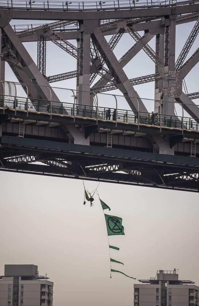 An activist from Extinction Rebellion dangles from the Story Bridge in a hammock as part of protests in Brisbane. Picture: AAP Image/Glenn Hunt