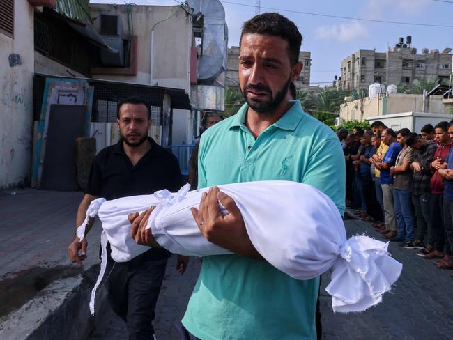 A Palestinian man carries the body of a child killed during Israeli shelling in the southern Gaza Strip, on October 10, 2023. Picture: SAID KHATIB / AFP