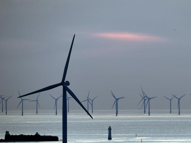 (FILES) In this file photo taken on May 14, 2019 New Brighton lighthouse is pictured at sunset, in New Brighton, at the mouth of the river Mersey, in north-west England on May 14, 2019, with the Burbo Bank Offshore Wind Farm visible on the horizon. - Britain, a global leader in offshore wind energy, plans to make the sector one of the pillars of its transition to carbon neutrality in the coming decades. The country aims to quadruple its offshore electricity production capacity by 2030 by utilising the windswept North Sea and a favourable policy environment. (Photo by Paul ELLIS / AFP)