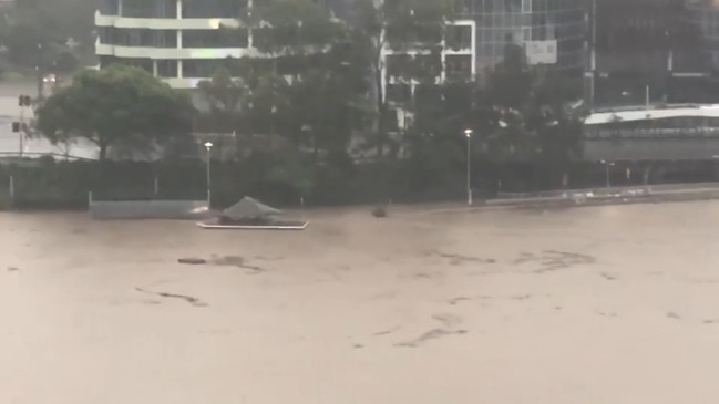 Debris and pontoons float down the flood swollen Brisbane River