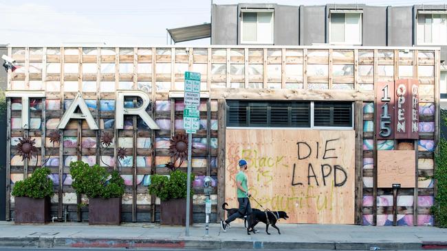 A man with a mask walks by graffiti after the aftermath of demonstrations on Fairfax Avenue in Los Angele. Picture: Valerie Macon / AFP