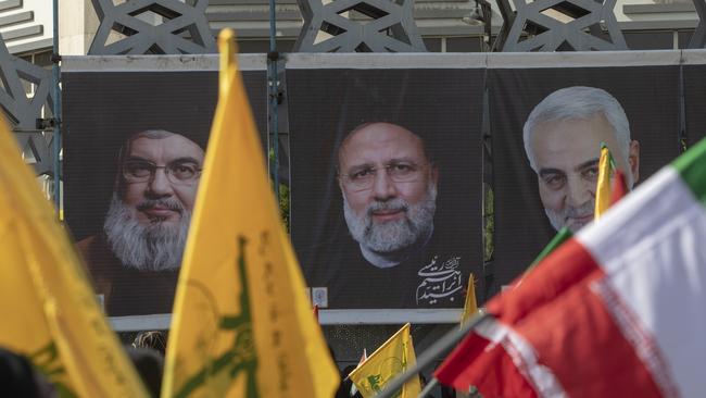 The people of Iran wave flags in front of the picture of Hassan Nasrallah, the Secretary General of Lebanon's Hezbollah, and the rest of the dead killed in an Israeli airstrike in the southern suburbs of Beirut. Picture: Majid Saeedi/Getty Images