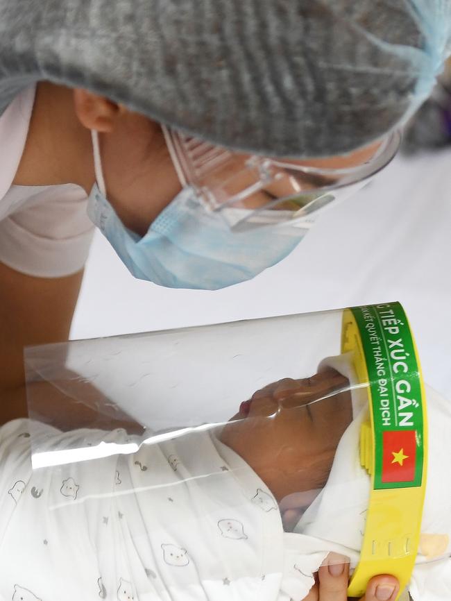 A nurse holds a newborn baby wearing a face shield at the National Maternity Hospital in Hanoi. Vietnam has had just 288 confirmed cases, in part through extensive quarantining. Picture: AFP