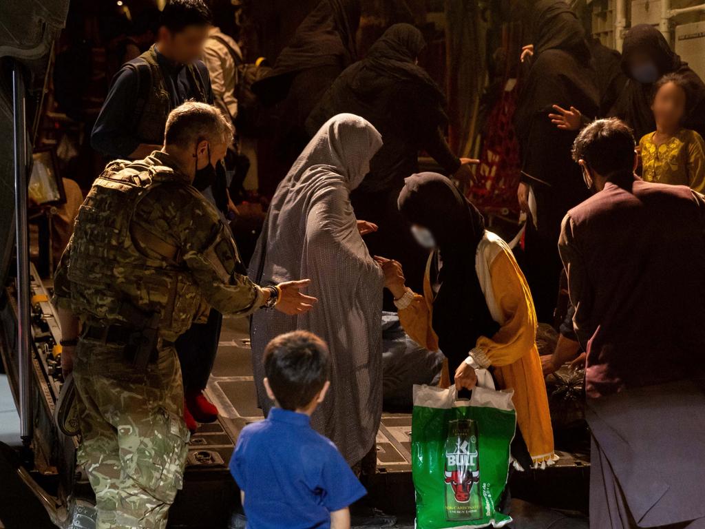 A Royal Air Force member assists evacuees from Afghanistan as they disembark a Royal Air Force C-130 Hercules. Picture: Defence