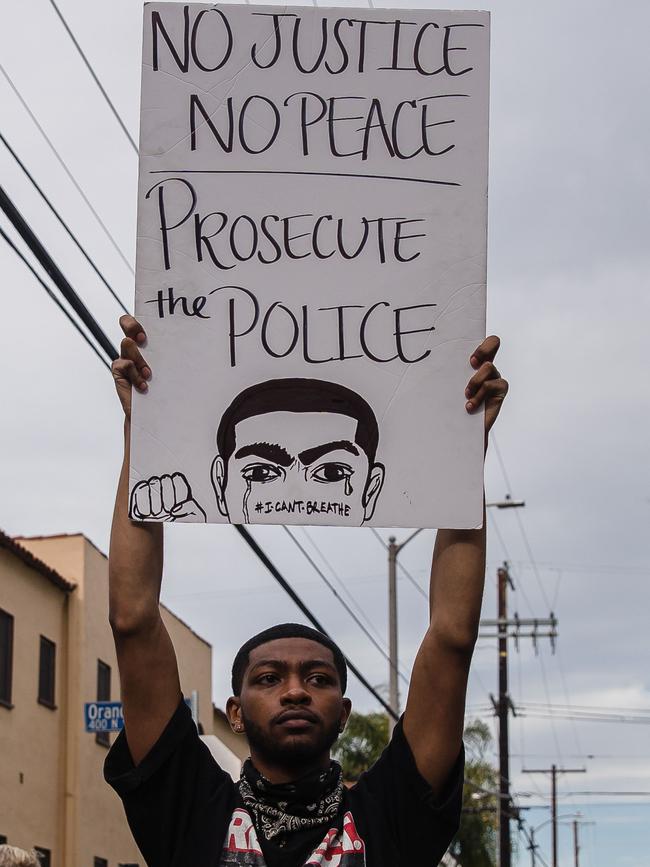 A demonstrator holds a sign in front of the police in Los Angeles.