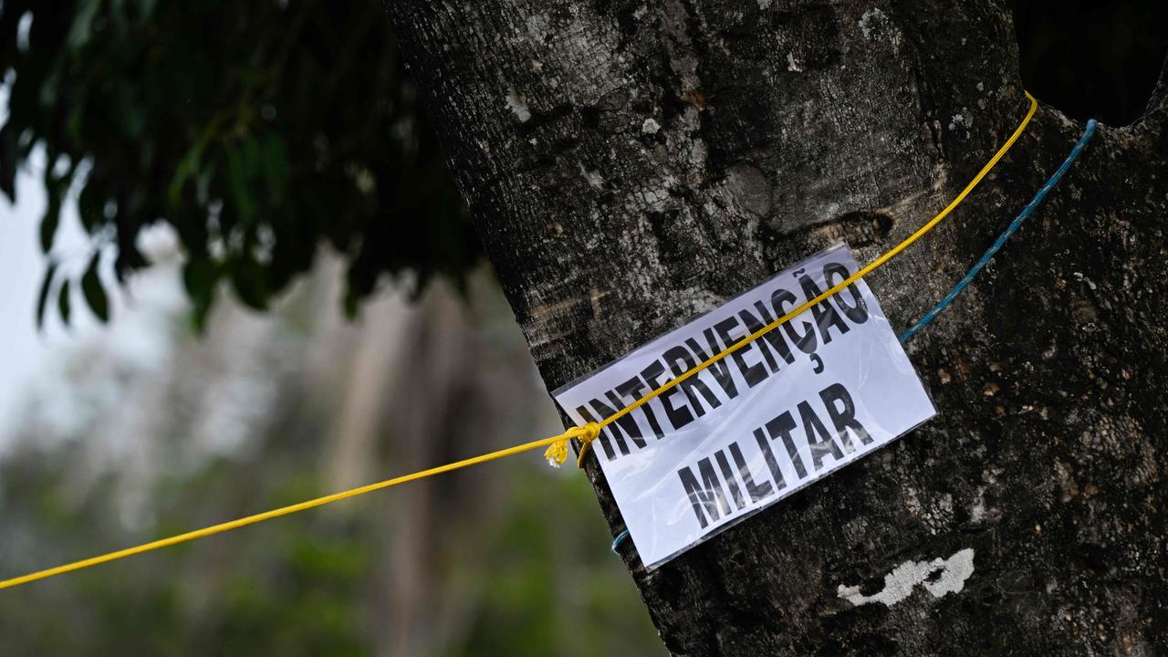 A sign on a tree reading "Militay Intervention" is seen as soldiers dismantle the camp set up by supporters of Jair Bolsonaro. Picture: AFP