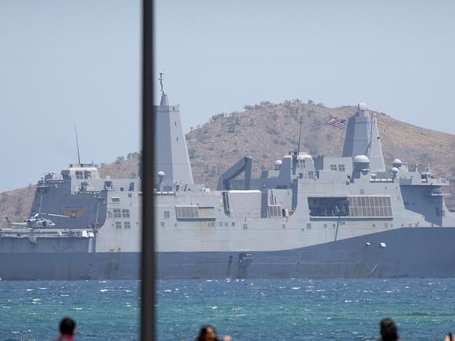 Visitors pose for photos outside of APEC Haus, the main venue of the APEC Economic Leaders' Week Summit as the US Navy ship USS Green Bay is anchored just offshore in Port Moresby, Papua New Guinea, Wednesday, Nov. 14, 2018. After three decades of promoting free trade as a panacea to poverty, the APEC grouping of nations that includes the U.S. and China is holding its lavish annual leaders meeting in the country that can least afford it. (AP Photo/Mark Schiefelbein)