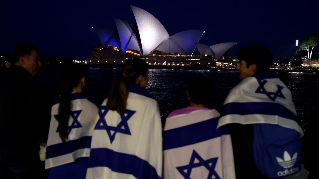 People with Israeli flags watch the Opera House while it is illuminated in blue to show solidarity with Israel in Sydney. Picture: David GRAY / AFP