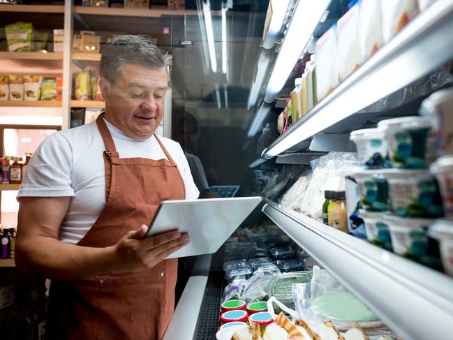 Happy man working at a grocery store doing the inventory - small business concepts